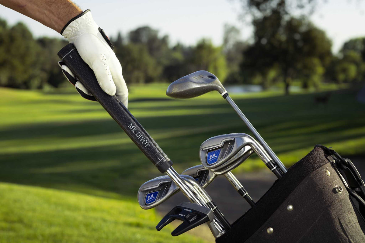 Golfer pulling MR. DIVOT  grip-first from a golf bag on the course, no bending